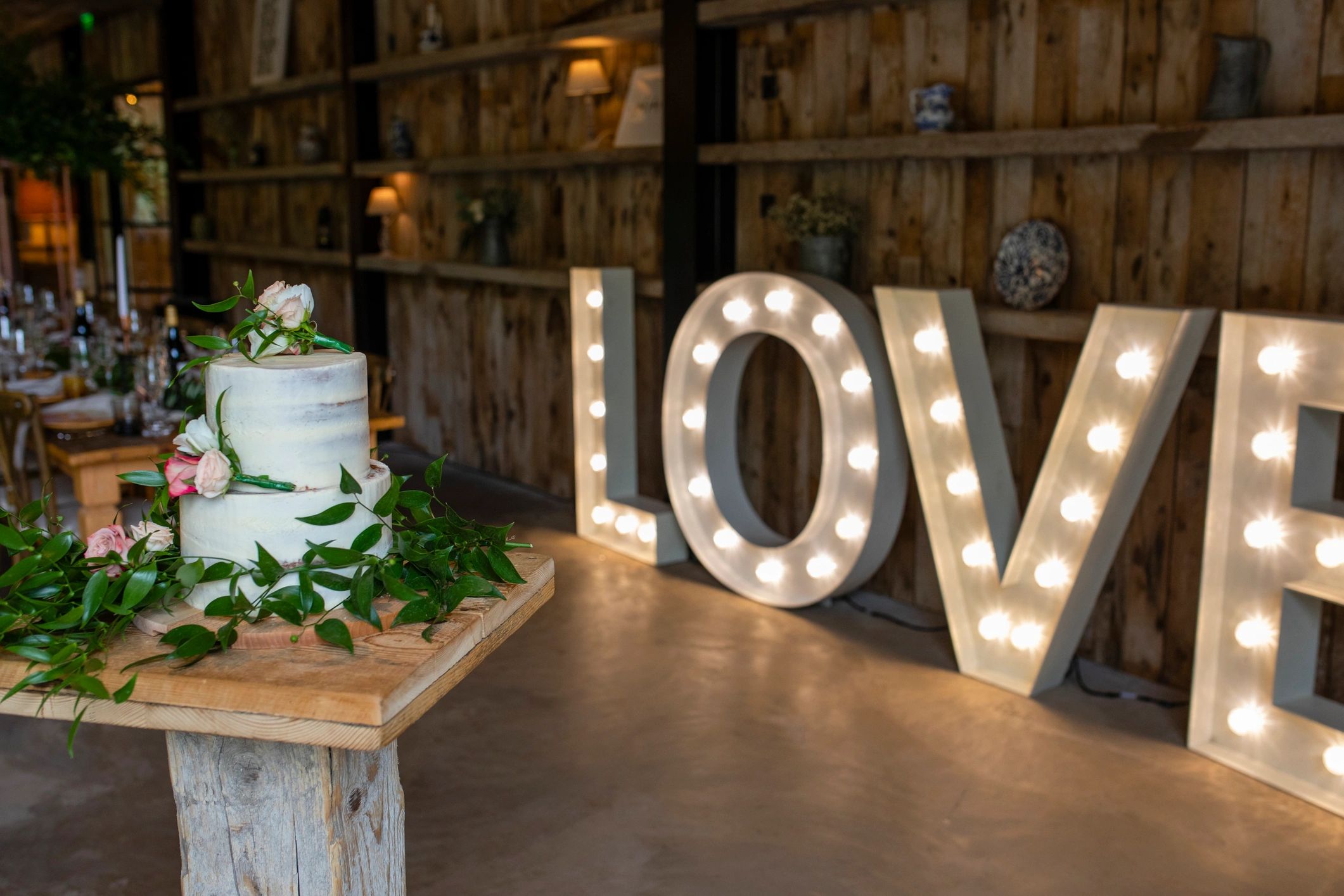 Wedding reception decor with cake and illuminated love letters